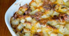 a casserole dish with potatoes and meat in it sitting on a wooden table