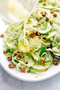 a white plate topped with cucumber and lettuce next to a spoon