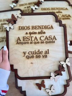 a person holding a wooden plaque with butterflies on it that reads, dios bendiga a muerti aesta cas