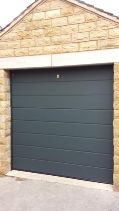 a grey garage door in front of a brick building