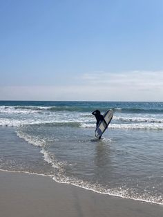 a person holding a surfboard in the water at the beach with waves coming in