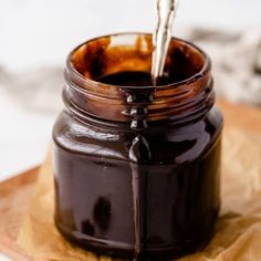 a jar filled with liquid sitting on top of a piece of wax paper next to a spoon