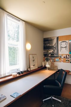 an office with a desk and chair in front of a large window that has pictures on it