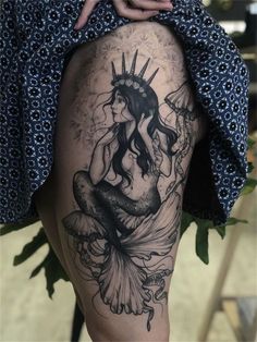 a woman with a crown on her head is sitting in front of a tattoo design