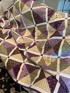 a purple and white quilt sitting on top of a bed