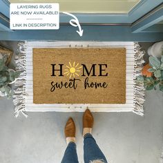 a person standing in front of a door mat that says home sweet home