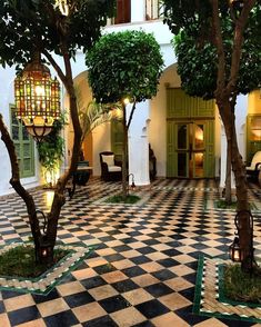 an indoor courtyard with potted trees and lanterns on the ceiling is decorated in black and white checkered tile