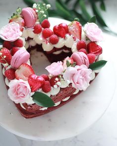 a heart shaped cake decorated with strawberries and flowers