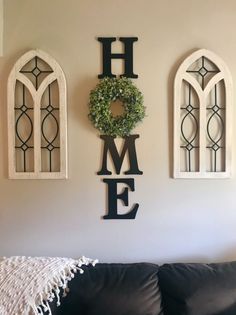 the word home is hanging on the wall next to two arched windows and a wreath