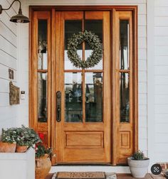 the front door is decorated with wreaths and potted plants on the porch area