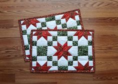 two red and white quilted placemats sitting on top of a wooden floor