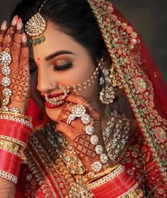 a woman in red and gold bridals with her hands to her face, looking down