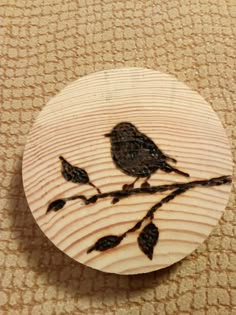 a wooden button with a bird sitting on a branch painted on it's side