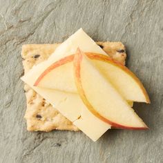 an apple slice and some crackers on a stone surface