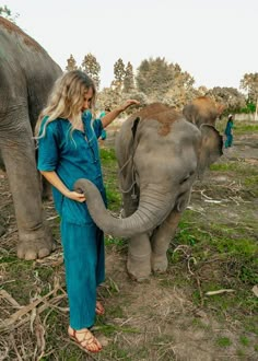 a woman standing next to an elephant in a field