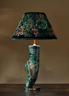 a lamp with a green shade on top of it and a flower design on the base