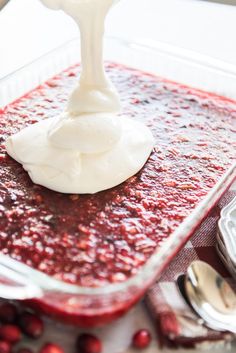 a spoon is being used to dip cranberry sauce in a glass casserole dish