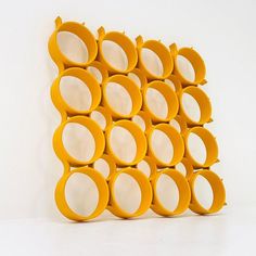 there is a yellow sculpture made out of circles on the wall and in front of it