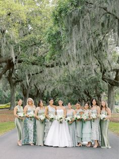 a group of women standing next to each other in front of trees with spanish moss