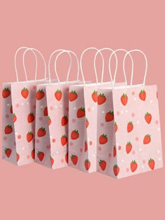 three bags with strawberries on them are hanging from the handles, and one is pink