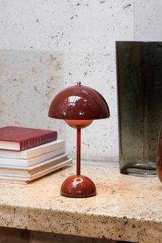 a brown table lamp sitting on top of a counter next to a stack of books