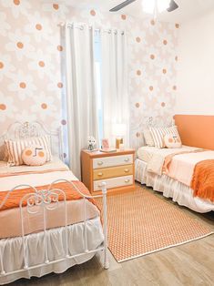 two beds in a bedroom with orange and white decor