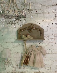 a chandelier hanging from the side of a brick wall next to a shelf with shoes on it