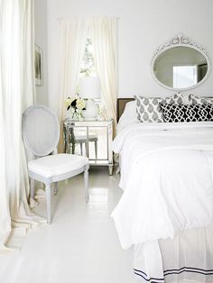 a bedroom with white furniture and curtains