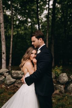 a bride and groom embracing in the woods