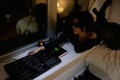 a woman sitting in front of a window with a keyboard and mouse