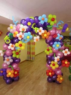 a bunch of balloons that are in the shape of an arch with flowers on it