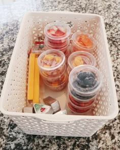 several plastic containers filled with food sitting on top of a marble countertop in front of a white basket