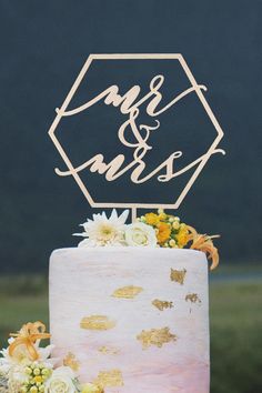 a wedding cake decorated with flowers and gold foil is displayed in front of the camera