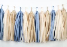 four different colored tassels hanging on a wall with one blue and the other beige