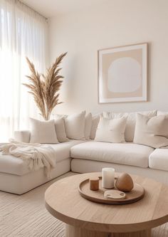 a living room with white couches and pillows on top of the sofa is next to a coffee table