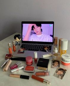 an open laptop computer sitting on top of a table filled with cosmetics and other items