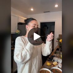 a woman standing in front of a table filled with bowls of food and holding a spoon