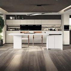 a modern kitchen with white cabinets and wood flooring is pictured in this image, there are plants on the counter