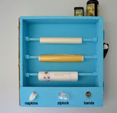 a blue box with three different types of items in it and two cell phones on the wall