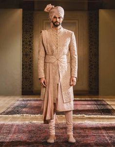 a man in a turban standing on a rug with his hands in his pockets