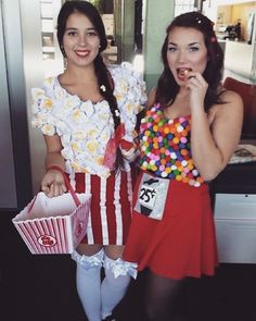 two women dressed in costumes posing for the camera with popcorn bags and candy on their mouths