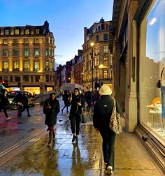 people walking down the street with umbrellas on a rainy day