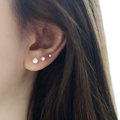 a close up of a woman's ear with three small white stones