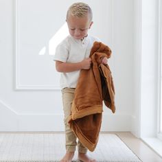 a young boy holding onto a brown towel