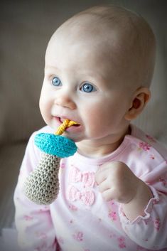 a baby is chewing on a crocheted toy