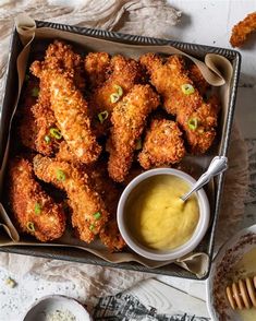 chicken wings with mustard and dipping sauce in a tray on a table next to utensils