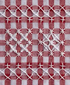 a red and white checkered table cloth with small flowers on it, as well as the cross stitch pattern