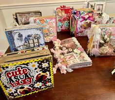 there are many small boxes on the table with flowers and pictures in them, all stacked up next to each other