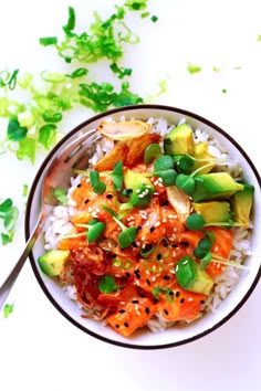 a bowl filled with rice and vegetables on top of a white table next to a fork