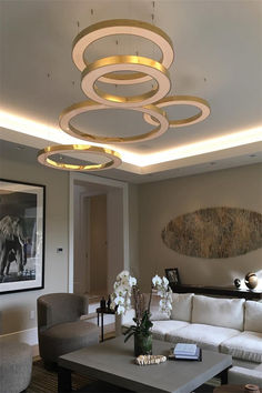 a living room filled with white furniture and lots of lights on the ceiling above it